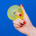 Hand holding a yellow donut-shaped object against a blue background