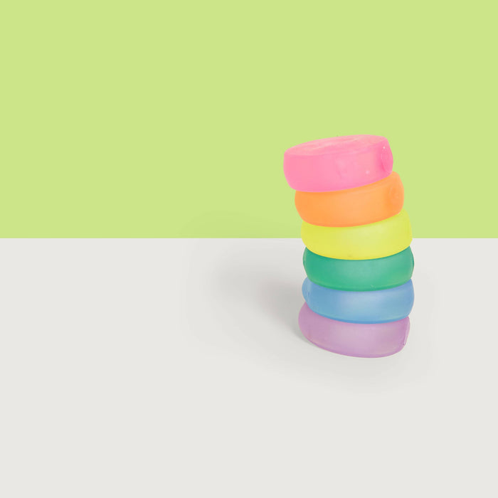 Stack of colorful rings on a white surface with a green background