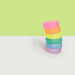 Stack of colorful rings on a white surface with a green background