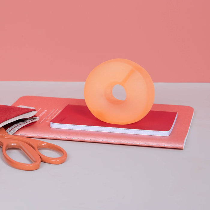 Orange ball on pink books with scissors on a light gray surface and pink background
