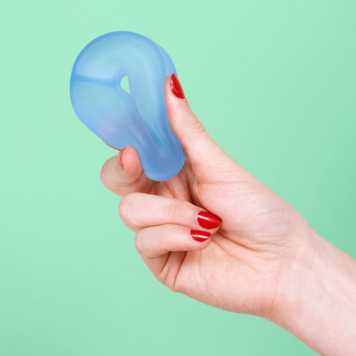 Hand holding a blue silicone product against a green background
