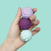Hand holding three textured stress balls against a light blue background