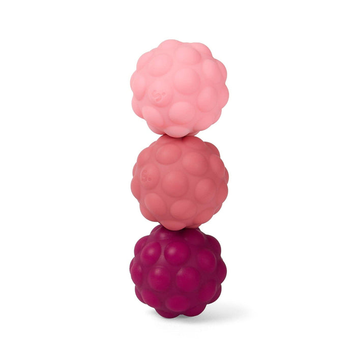 Three stacked raspberry-shaped silicone teething toys in light pink, medium pink, and dark magenta, arranged vertically on a clean white background.