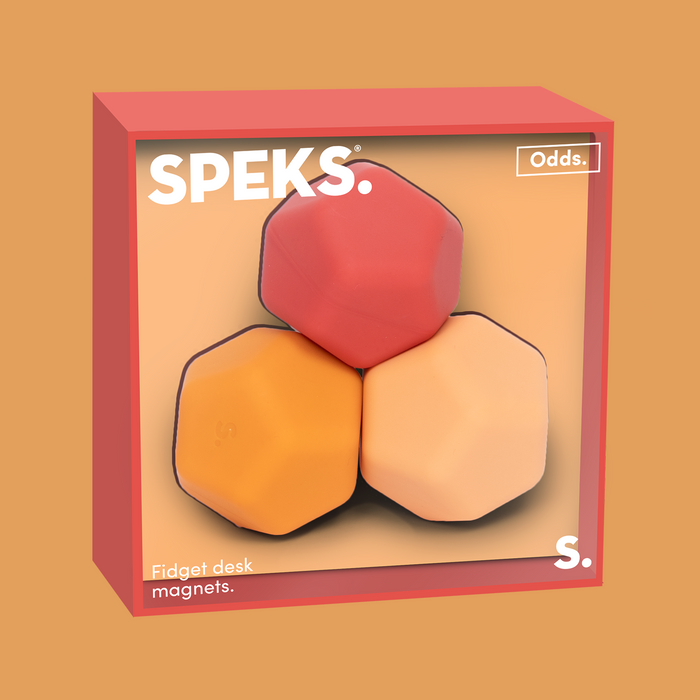 A product box for SPEKS Odds Fidget Desk Magnets, featuring three hexagonal magnets in red, orange, and light peach, displayed inside a red box on a solid tan background.