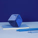 Blue geometric object and pens on a blue surface with a dark blue background