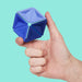 Hand holding a blue geometric stress ball against a teal background