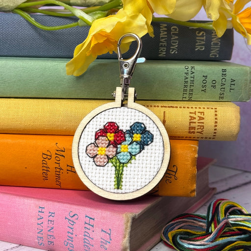 floral design in emboridery hoop displayed in front of colourful books