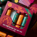 A boxed set of decorative Christmas crackers labeled 'The Traitors 2026' arranged on a dark wooden table with role cards, tickets, and additional crackers nearby.