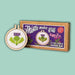 Cross stitch mini kit with a completed design and packaging on a light green background