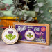 Cross-stitch mini kit with a completed design and packaging on a wooden surface.
