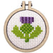 Embroidery hoop with a purple flower and green leaves on white fabric