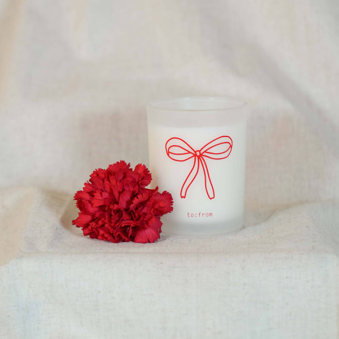 Candle with a red bow design and a red flower on a white background