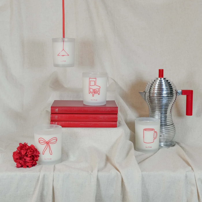 Decorative items including candles, books, and a teapot on a white fabric background