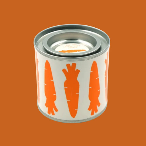 Tin candle container with carrot design on an orange background