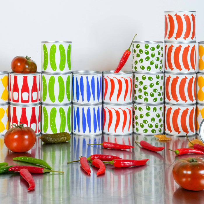 Colorful stacked cans on a reflective surface with tomatoes and peppers.