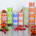 Colorful stacked cans on a reflective surface with tomatoes and peppers.