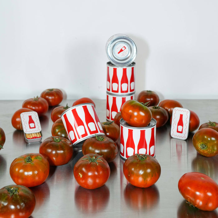 Tomatoes and cans with red and white labels on a reflective surface