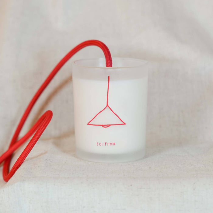 White candle with red lamp design and string on a white background