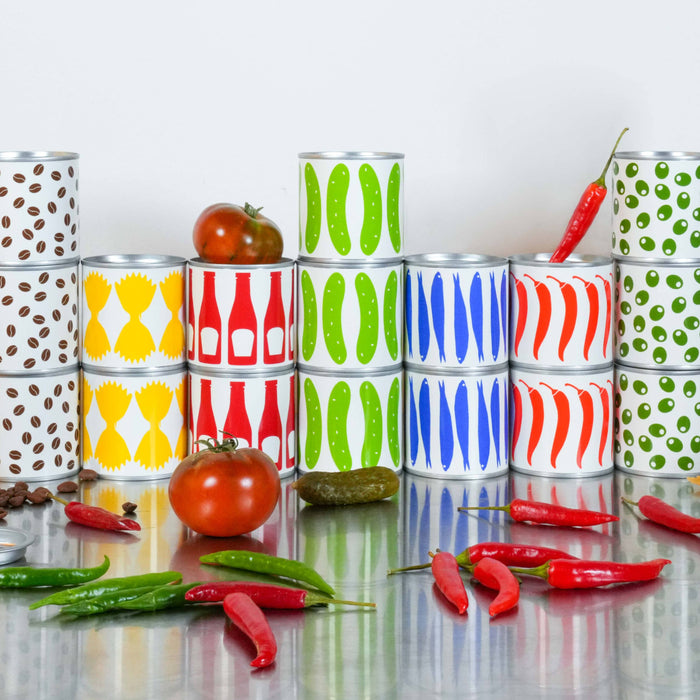 Colorful stacked cans on a reflective surface with tomatoes and peppers.