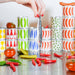 Colorful stacked canisters on a kitchen counter with a person's hand reaching out holding a sardine.