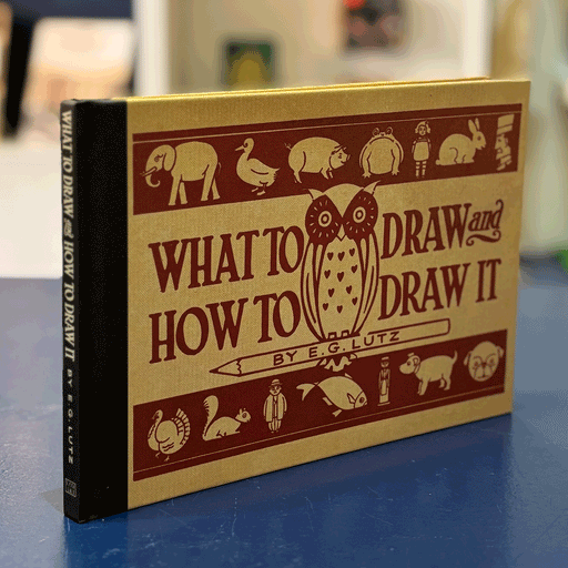 book titled 'what to draw and how to draw it' on top of navy desk with blurred background