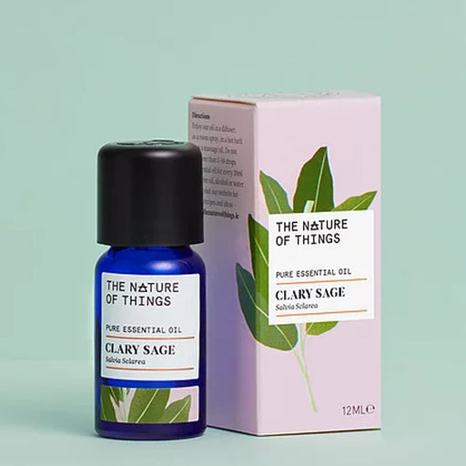 Clary Sage essential oil blue bottle beside an pink product box with an illustration of green leaves on front against a blue background