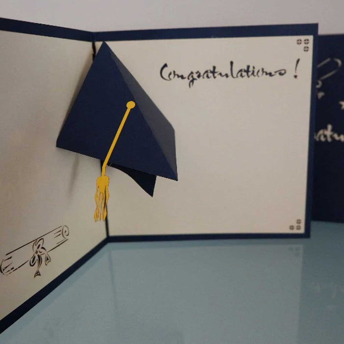 navy and white open greeting card with 'congratulations' written in cursive and a 3D navy graduation hat with a gold tassel 
