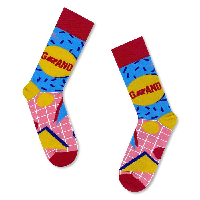 a pair of blue , pink and yellow socks with white line grid and red  at toes and ankles holes. the word grand in written in red inside a yellow circle