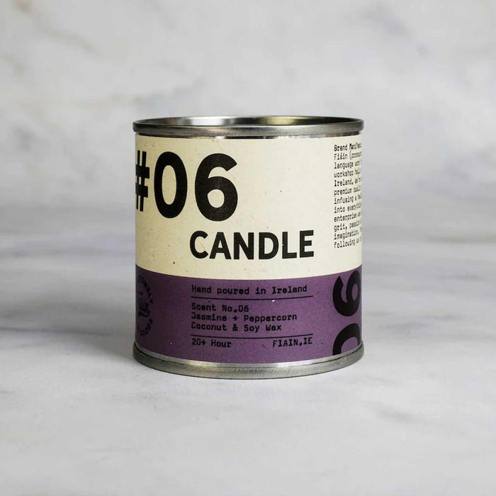 round metal tin with white and purple label with 06 candle in black text, against a grey backdrop