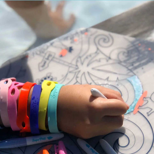 child's hand wearing colourful bands on arm and hold a marker, drawing on a printed placemeat