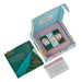 open blue gift  box with pink interior containing 2 green product boxes and one blue. Blue and green pamphlet to left of gift box and white an d pink card below box
