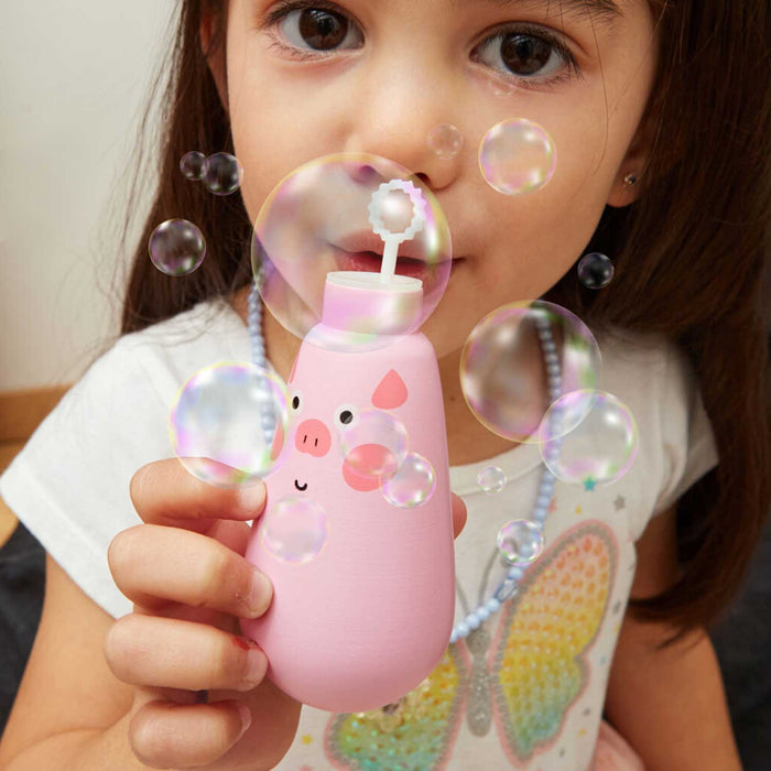young girl blowing bubbles from a pink bubble bottle with a pigs face