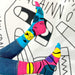 pair of legs in blue jeans and pink and blue socks with black lines against a blank and white background