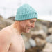 side profile of man, topless outside with a blue woollen hat on head
