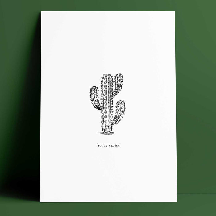 white rectangle print with an black lined illustration of a four pronged cactus in the centre and 'you're a prick' in text below the cactus. Print is in front of a green backdrop