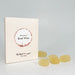 A cream rectangular product box with a circular white and sand coloured label reading 'flavours of Rose Wine' and smaller text photographed on a light fabric surface next to yellow gummies.