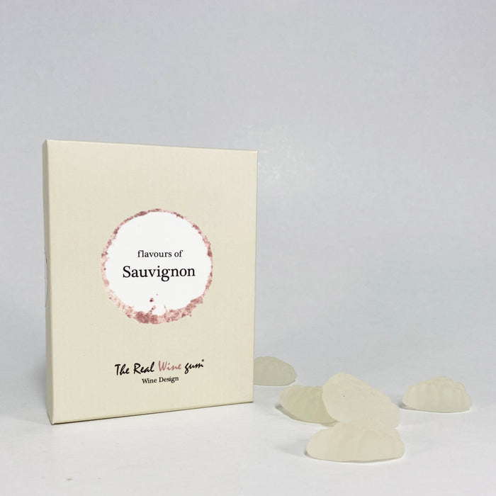 A light green rectangular product box with a circular white and sand coloured label reading 'flavours of Sauvignon' and smaller text 'The Real Wine Gum Wine Design,' photographed against a white surface beside white gummies.