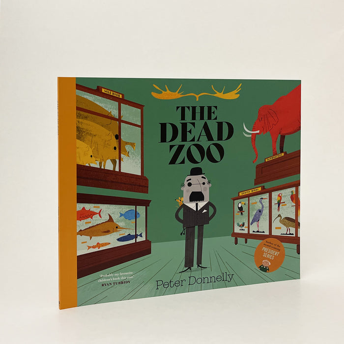 the book is standing upright on a white background. the book has a yellow spine and a colourful picture of the inside of the dead zoo and mr. grey on it. the main colour is turquoise