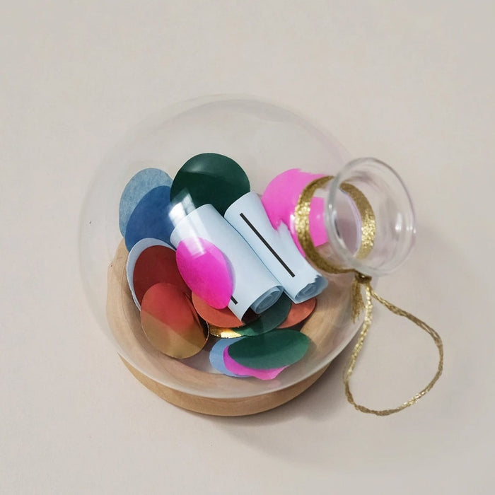 glass globe ornament filled with coloured paper discs and two paper  scrolls