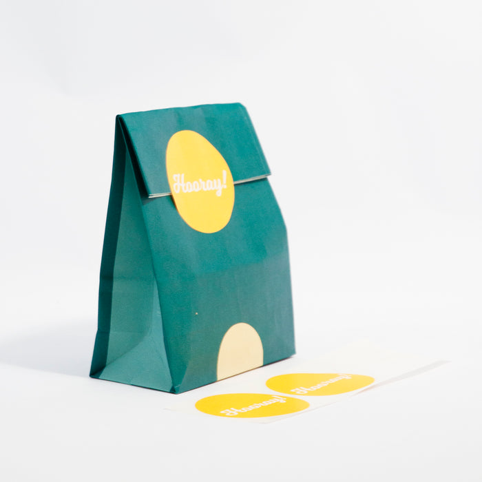 two tone turqoise mini reusable gift bag with bright yellow stickers that say 'hoorary!' on them