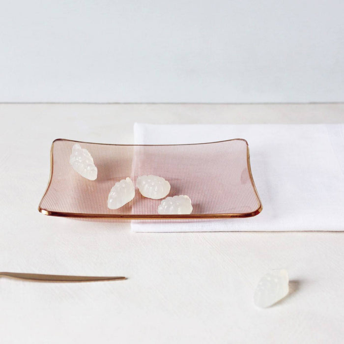 White coloured gummies on an orange glass dish against a cream and white surface.