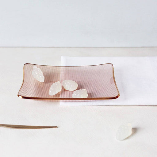 White coloured gummies on an orange glass dish against a cream and white surface.